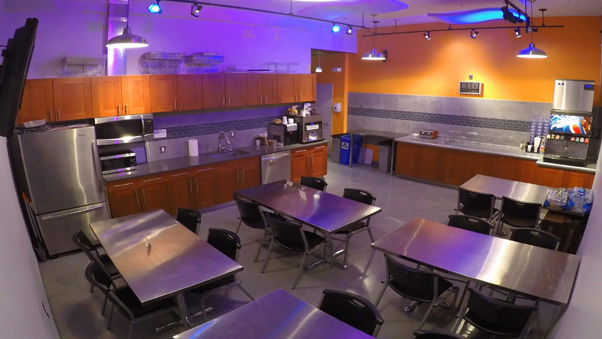 ThunderShot Studios break room with stainless steel tables, black chairs, kitchen appliances and purple accent lighting