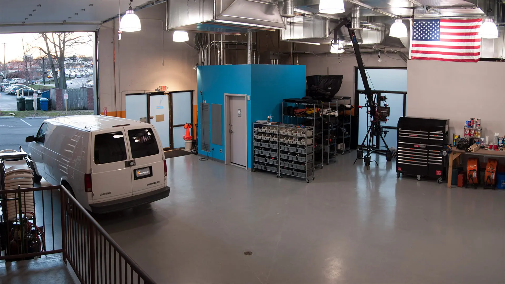 Indoor truck bay at ThunderShot Studios with a white van, equipment carts, a camera crane and an American flag