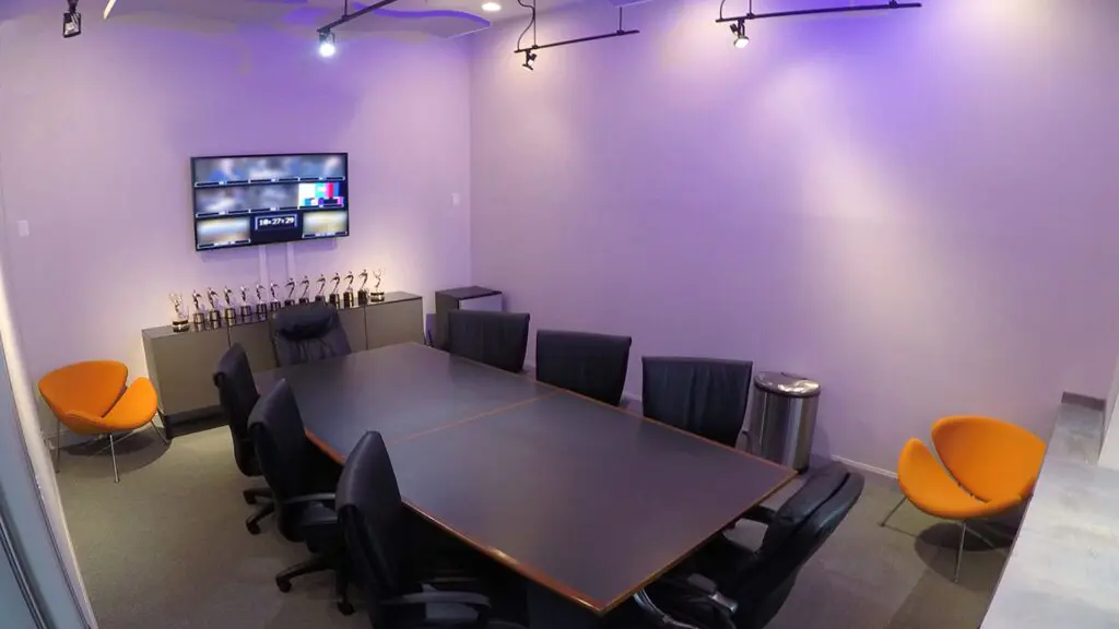 ThunderShot Studios conference room with a long table, black office chairs, orange accent chairs, wall monitor and awards