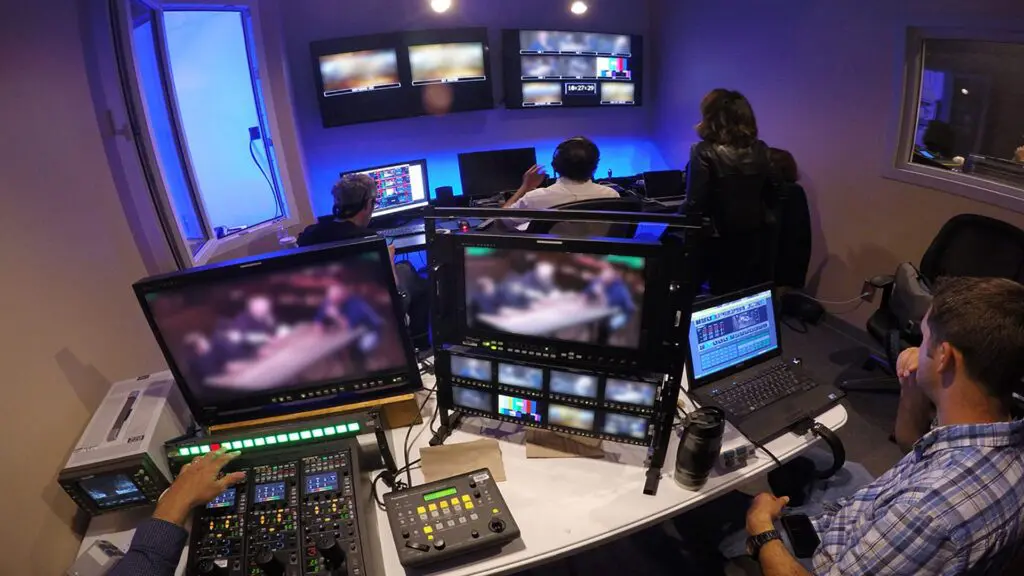 Control room with crew at video monitors, a switcher and audio controls