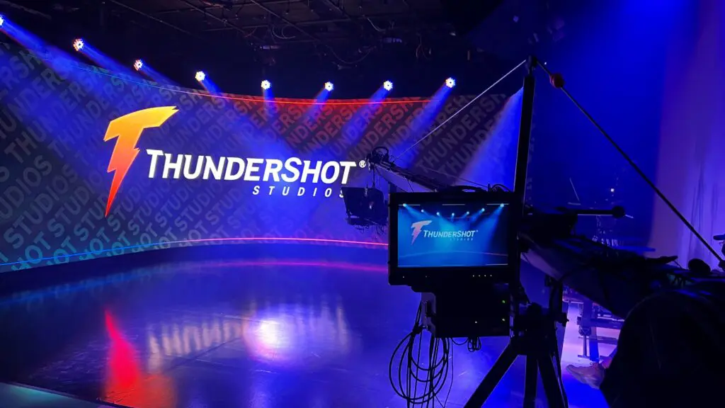 Curved LED wall displaying the ThunderShot Studios logo under blue lighting, with a camera on a jib